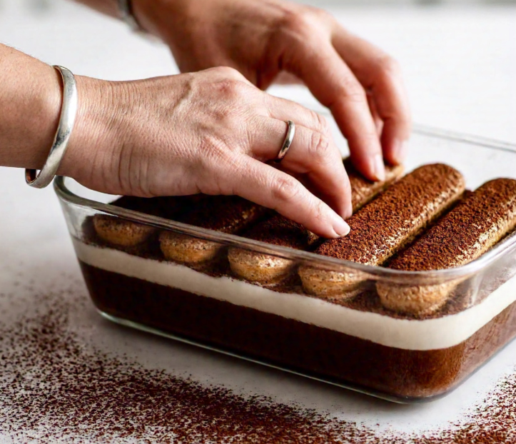 A step-by-step guide to assembling gluten free tiramisu, showing layers of coffee-soaked ladyfingers and creamy mascarpone in a glass dish.