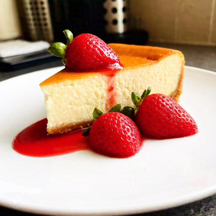 Classic baked cheesecake with fresh strawberries and sauce.