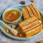 A golden honey bun cake topped with a shiny glaze, served on a white plate with a fork beside it.