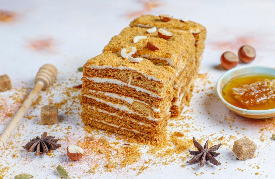 A slice of honey bun cake showing its cinnamon swirl layers, served with a cup of coffee on the side.