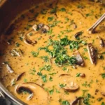 Bowl of creamy mushroom soup with fresh herbs and bread on the side