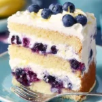 A slice of Lemon Blueberry Cake with blueberries and lemon zest on top.