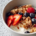 A bowl of creamy scrambled oats topped with fresh berries and nuts