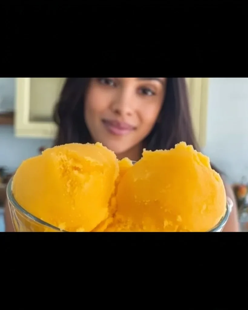 A vibrant bowl of 1-ingredient mango sorbet topped with fresh mint leaves.